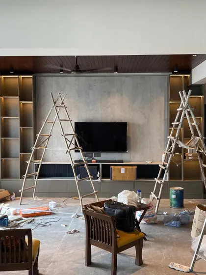 The 'before' phase of a living room project in Lotus 300, Noida. This image shows the space during construction, with ladders and materials, as our team works on the custom-built TV unit and shelving.