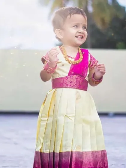 Another joyful moment captured in her traditional attire. The bright pink blouse and belt feature a lovely brocade pattern that contrasts beautifully with the light-colored skirt.