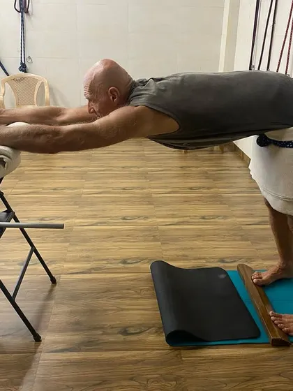 The same senior student using a chair and ropes for a supported forward bend, creating length in the spine.