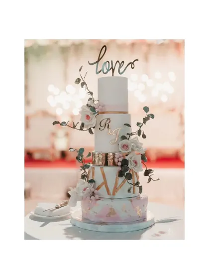 A beautiful, multi-tiered wedding cake adorned with flowers and a "love" topper. This shot captures one of the sweet, artistic details of the reception.