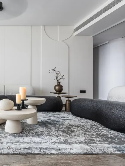 This angle highlights the subtle wall detailing behind the serpentine black sofa. The gentle arches in the paneling echo the curves of the furniture, creating a cohesive and thoughtfully designed backdrop.
