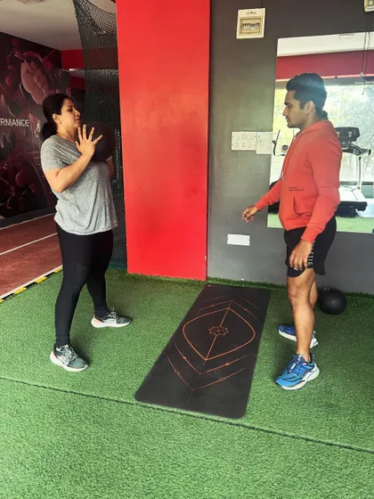 A coach instructs a client on proper medicine ball handling, ensuring she understands the movement before starting the exercise.