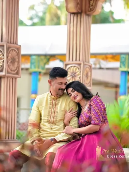 A tender moment between a couple in traditional Indian outfits. The woman rests her head on her partner's shoulder, showcasing the comfort and elegance of the rental attire.