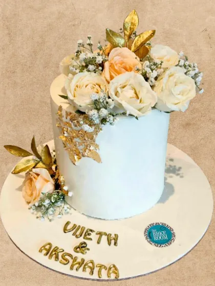 A beautiful engagement cake topped with fresh peach and white roses and delicate gold leaves. This minimalist design is perfect for a chic and modern celebration.