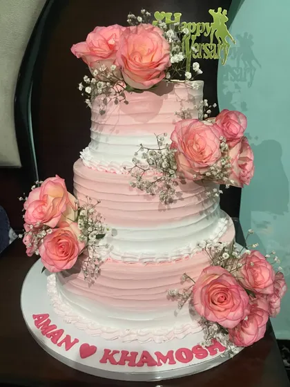 This three-tiered anniversary cake combines classic elegance with natural beauty. I decorated the eggless cake with soft pink and white frosting and adorned it with fresh, fragrant roses, creating a romantic and sophisticated look for a very special day.