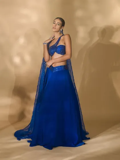 A lookbook image for Nikhil Thampi's 'Sapphire Edit'. The model's pose is designed to showcase the entire ensemble, including the sheer, embellished cape and flowing skirt.