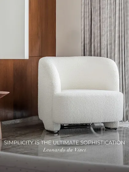 "Simplicity is the ultimate sophistication." This corner embodies that philosophy. A plush white bouclé chair sits on a reflective marble floor, complemented by a simple wood side table and a sculptural lamp.