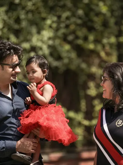 A candid shot of a family enjoying their time together outdoors, with the father holding their daughter.
