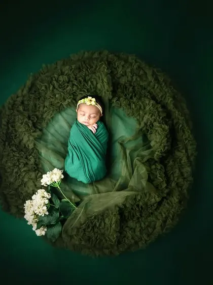 A beautiful overhead shot of a newborn wrapped in green, nestled in a soft, mossy bed. This creates a lovely, nature-inspired "nest" effect.