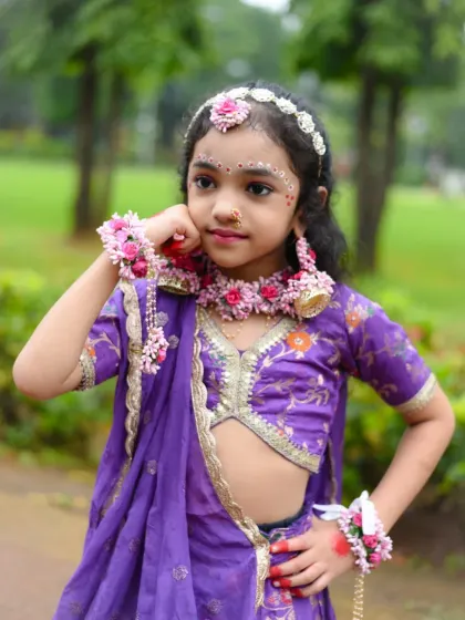 A classic, graceful pose that showcases the beautiful costume and floral accessories of the Radha attire.