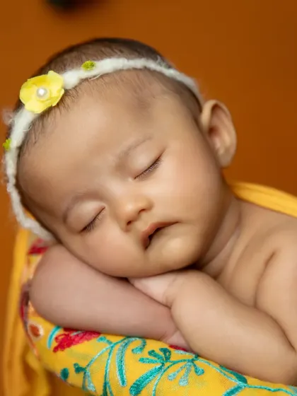 A close-up of a sleeping newborn's face, looking angelic during her mango-themed photoshoot.