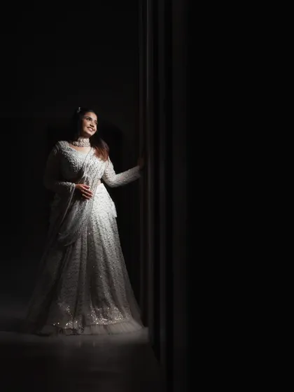 A beautiful low-key portrait of a bride in a white gown. The single light source illuminates her and creates a feeling of elegance and quiet confidence.