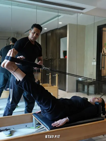 I believe in hands-on guidance. Here, I'm helping a client perfect her leg press form on the reformer, ensuring she engages the right muscles for maximum benefit and injury prevention.