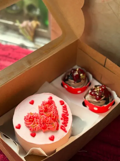 A romantic and pretty combo box with a pink bento cake decorated with intricate red piping. The two chocolate cupcakes are topped with a cherry and gold flakes for a touch of elegance.