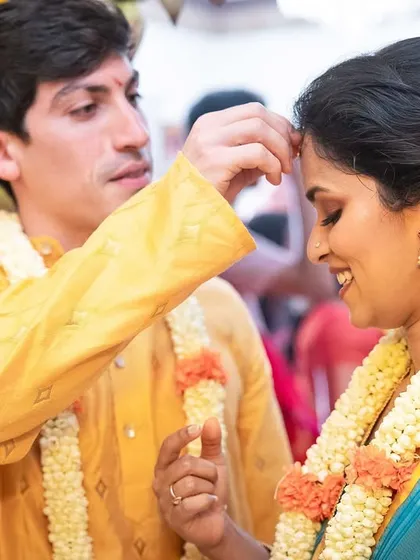 A groom applies the 'bindi' to his bride's forehead, a simple yet profound gesture of love and commitment.