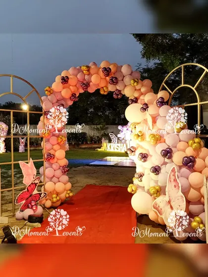 An elegant entrance gate framed with a cascading balloon arch in warm pastel tones, setting a sophisticated and whimsical mood.