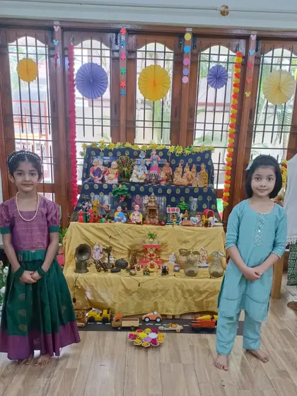Two friends stand together in front of our Dussehra Golu display. These celebrations are a wonderful opportunity for children to learn and share cultural experiences.