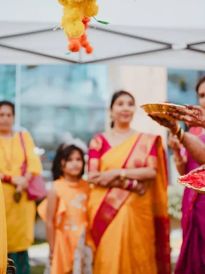 The bride, surrounded by family holding plates of flowers and blessings, ready for the ceremony to begin.