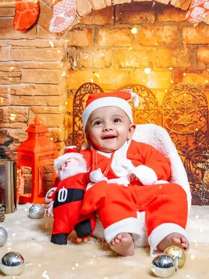 Celebrate the holidays with a special photoshoot. This little Santa is all smiles in our cozy Christmas setup, complete with a tree, fireplace, and gifts.