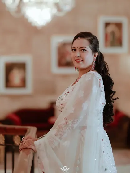 A beautiful portrait of a bride on a staircase, her white and pink lehenga on full display.
