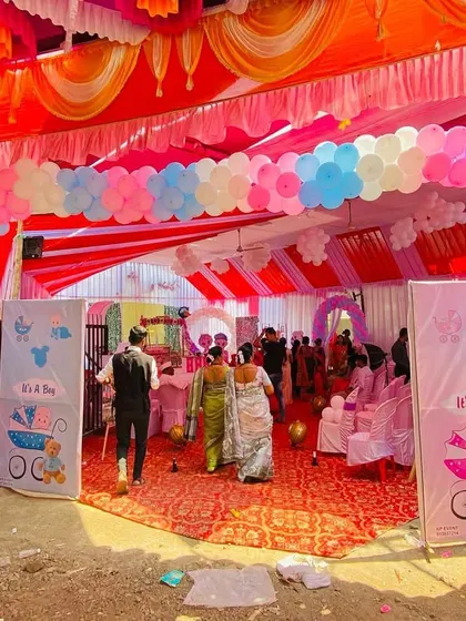 A wide view of a baby shower entrance under a large pandal, with a colorful balloon arch and welcome sign.