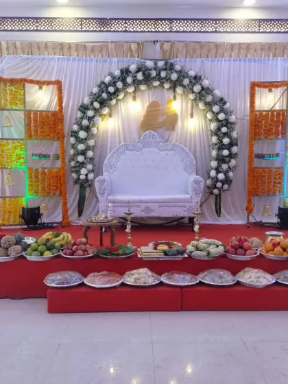 A baby shower stage prepared for rituals, with a full display of fruit platters and traditional items arranged in front of the main seating area.