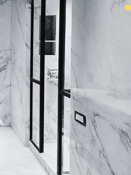 A detail from a bathroom in the 58WV project. The stark contrast between the black metal frame of the shower door and the heavily veined marble walls creates a bold, graphic statement.