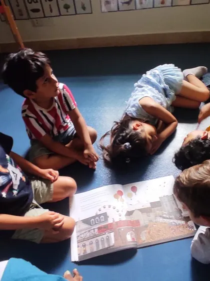 Snuggled up on the floor, a group of children is captivated by a storybook. Our cozy story times are a favorite part of the day for all age groups.