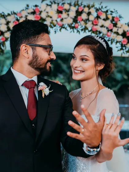 A happy portrait of a newly engaged or married couple, smiling at each other as they proudly show off their rings.