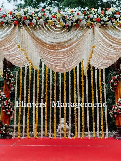 A grand traditional mandap, with pillars wrapped in flowers and a canopy made of draped tuberose garlands.