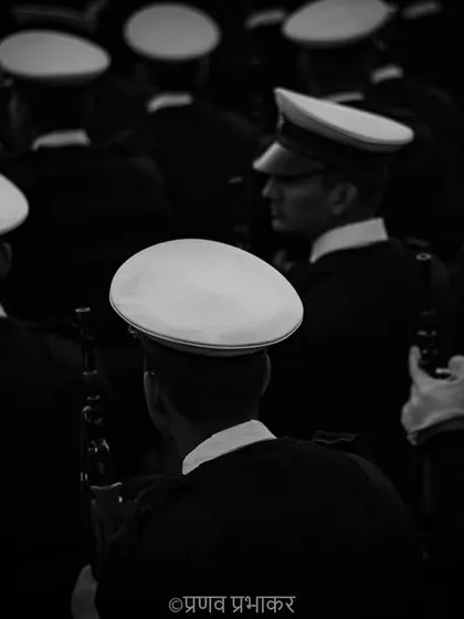 A different perspective on the parade. This high-angle, black and white photograph focuses on the pattern of the white caps, creating an abstract and artistic view of the marching contingent.