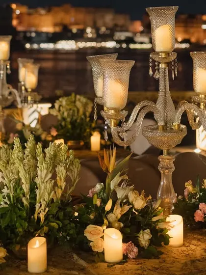 A close-up of the tablescape from the Udaipur event, focusing on the warm glow of candles within glass candelabras and lush floral arrangements. This detail shot emphasizes the romantic and luxurious ambiance we create.