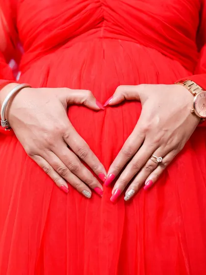 A close up shot focusing on the heart of the matter. Making a heart shape with your hands on your belly is a classic and sweet pose that symbolizes all the love you have for your baby.