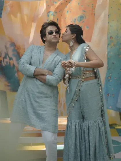 A playful moment between the couple, perfectly framed by the artistic and vibrant backdrop of their Haldi celebration.