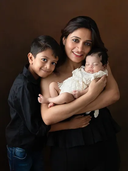 A mother holds her newborn daughter while her son stands proudly beside them. This portrait, shown in both color and black and white, captures the warmth of a growing family.