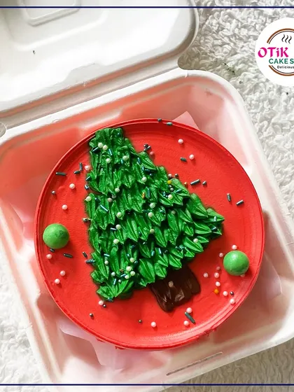 This Christmas tree bento cake is a fun and festive treat. The red base and green piped tree with sprinkles make it a delightful holiday surprise.