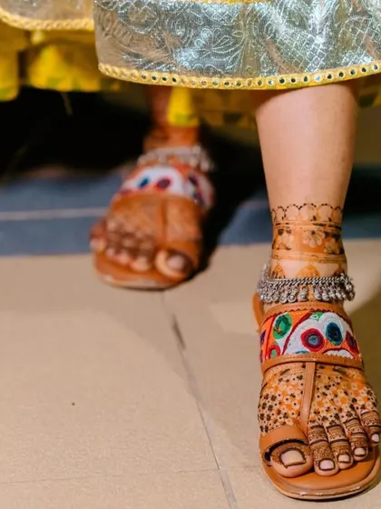A lovely shot of the bride's feet in traditional Kolhapuri sandals. The mehndi design peeks through, adding to the overall festive look.