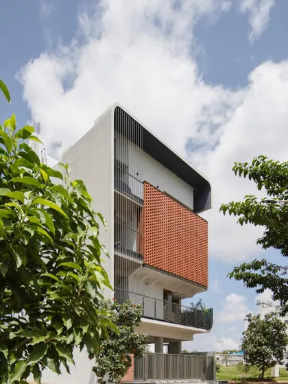 The C-shaped envelope of 'House Belaku' wraps around the structure, with the brick jali unifying the design.