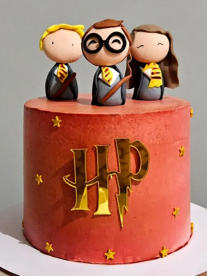 A closer look at the Harry Potter trio cake, highlighting the clean lines of the airbrushed finish and the golden HP logo.