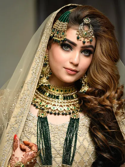 A breathtaking close-up of a bride in her gorgeous gold and green ensemble. This portrait highlights the flawless makeup, intricate jewelry, and the serene expression of the bride on her special day.