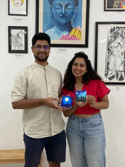 A couple with their miniature canvas paintings. The smiles say it all. It's about the shared experience as much as the art itself.