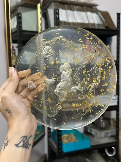 This piece preserves a baby's hand and foot casts in clear resin with gold flakes. It’s an incredibly touching way to remember how tiny they once were.