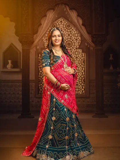 A full-length portrait showcasing the splendor of a traditional bandhani lehenga against an ornate, palace-themed backdrop.
