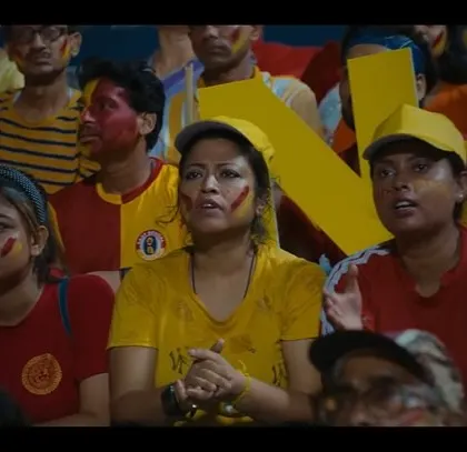 The faces of the fans tell the story in this shot from the East Bengal FC commercial. Their face paint and team-colored outfits show their unwavering support.
