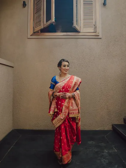 A portrait of a bride in a traditional red sari, looking elegant and happy at her Goa wedding.