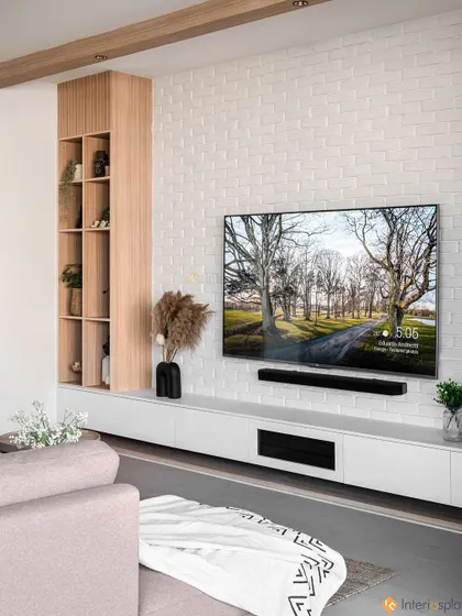 This minimalist TV unit includes a sleek white console and a built-in wooden shelving unit. It provides a perfect balance of hidden storage and open display space for books and decor.