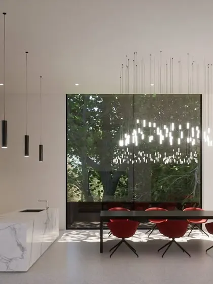 The open-plan kitchen and dining area in the Hyderabad residence, defined by a marble island and minimalist cabinetry. A large window frames a view of the garden, turning a simple meal into an experience connected with nature.