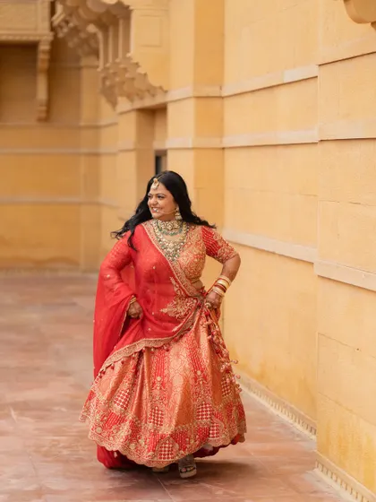 Nirzari in her element, her vibrant rust-red lehenga designed to celebrate her free-spirited and bubbly personality.