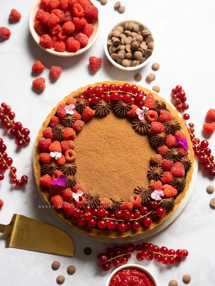 A beautiful flat lay of my Raspberry and Milk Chocolate Tart, surrounded by fresh raspberries and red currants.