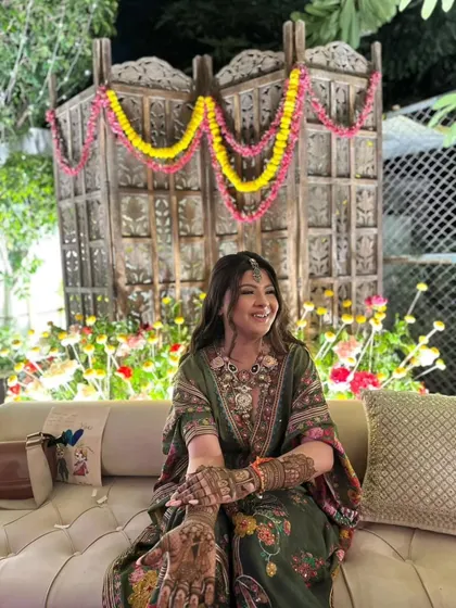 A candid shot of a beautiful bride during her mehandi ceremony. Her natural smile and the festive decor create a happy vibe.